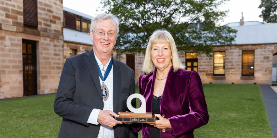 man and woman stand smiling holding a trophy