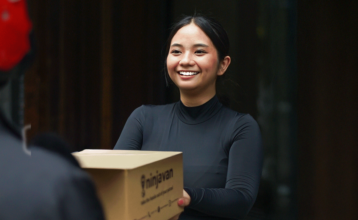 Woman passing a Ninja Van box to a rider.