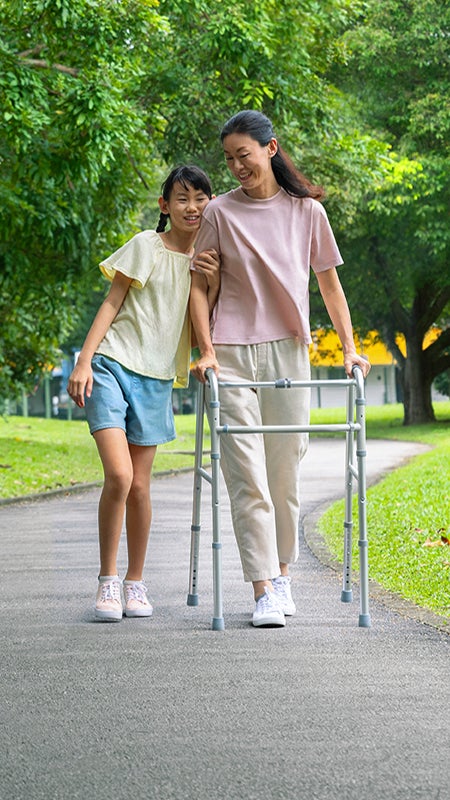 A woman using a walking frame walks with a child.