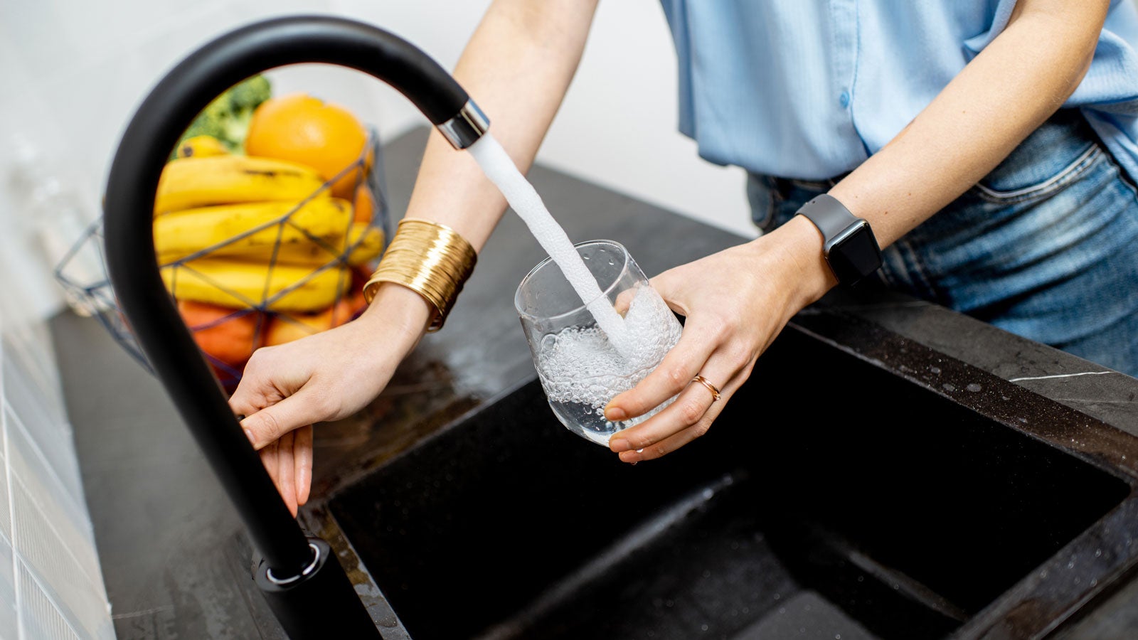 Person filling a glass of water at the kitchen sink.