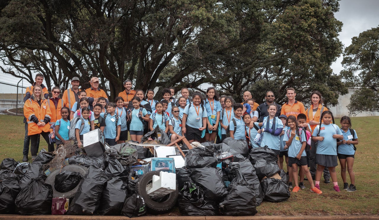 St Joseph's Grey Lynn School students, Watercare staff and volunteers stand proudly behind  their rubbish pile collected during the 2020 Sea Week beach clean up at and around the Māngere Wastewater Treatment Plant.