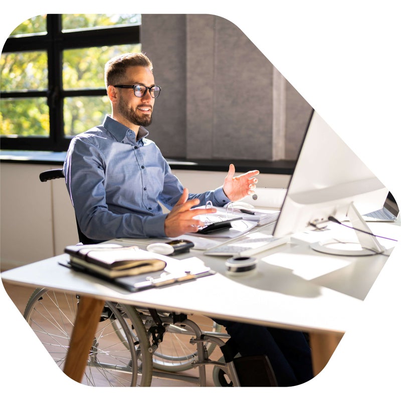 Image of man in a wheelchair who is sitting at his desk, talking to someone through a computer