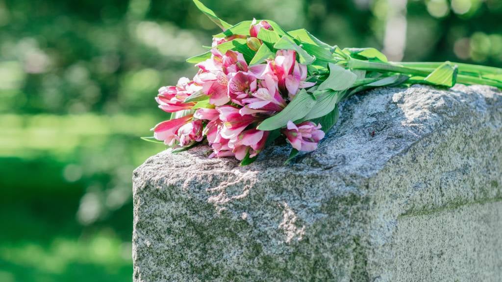 A bunch of pink flowers lay on tombstone 
