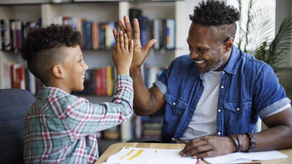 Father and son sit at desk completing homework