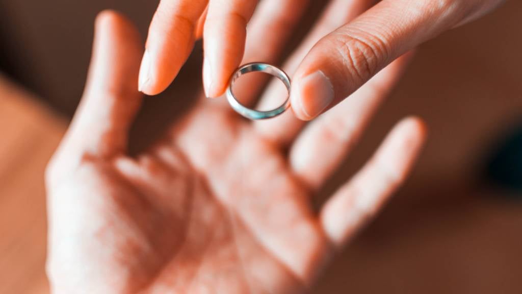 Woman takes off her wedding ring and puts it in a man’s hand