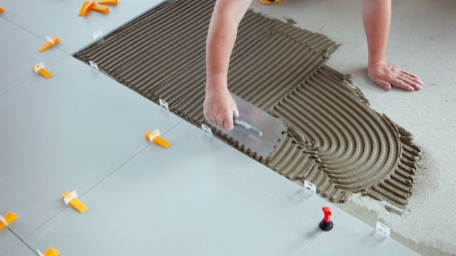 工人正在塗水泥鋪磁磚地板