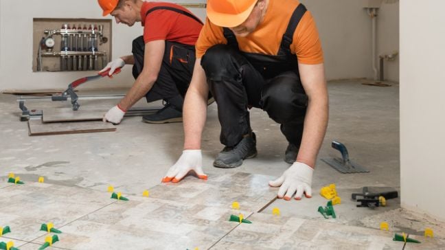 工人一邊鋪磁磚，一邊確認磁磚有無對縫