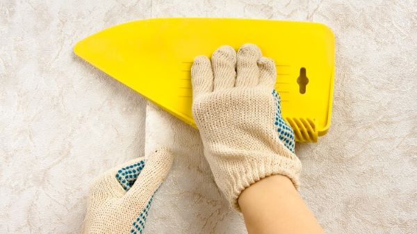 貼壁紙過程中，使用刮板協助黏貼能將壁紙黏得更牢
