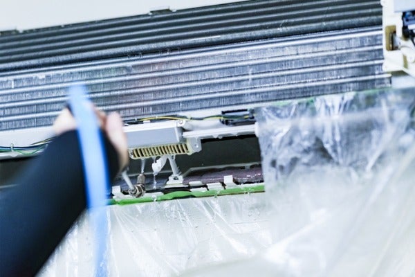 ▲師傅在清洗冷氣室內機時，會使用防水罩防止清洗時髒水噴濺