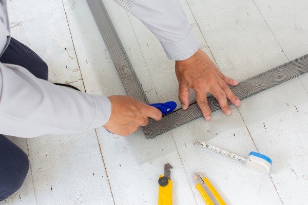 以壓輪依序將紗網與壓條壓入溝槽：固定紗網