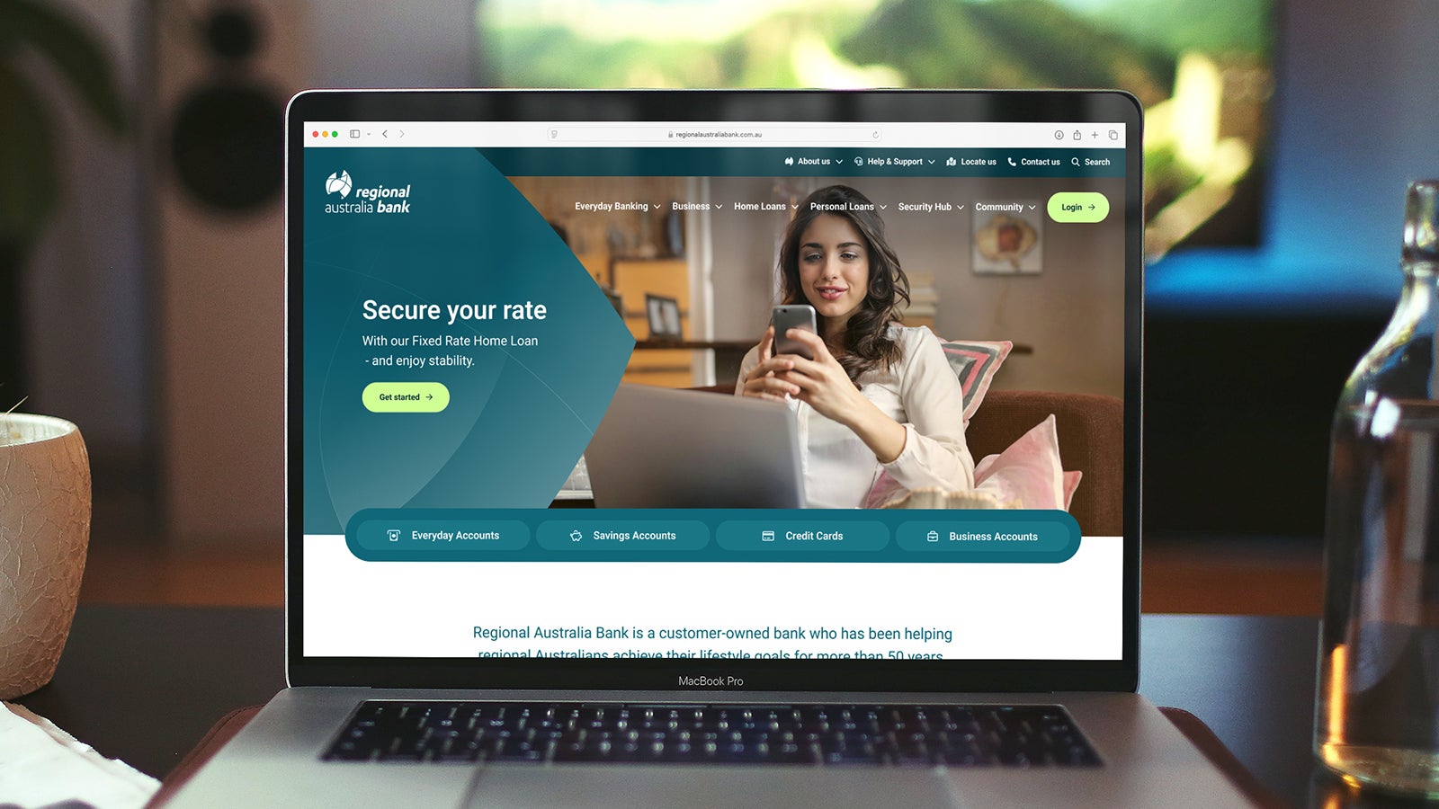 Regional Australia Bank | A laptop sitting on a desk next to a bottle of water showing Regional Australia Bank's website homepage | Devotion