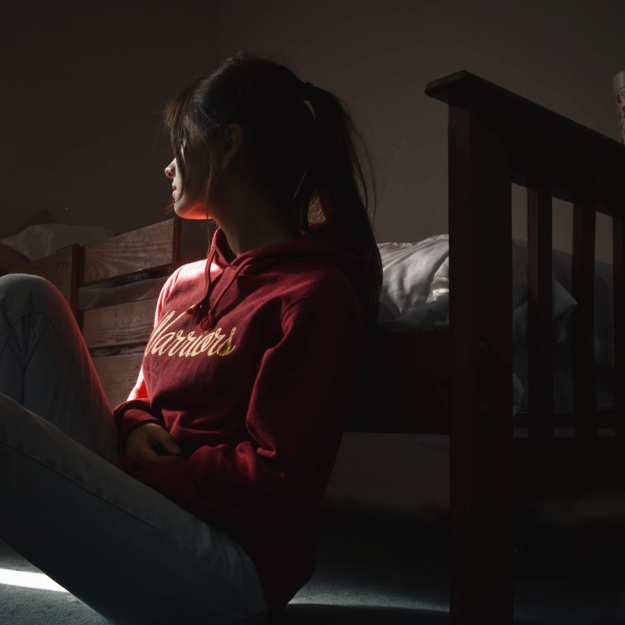 Woman in shadows sitting next to bed