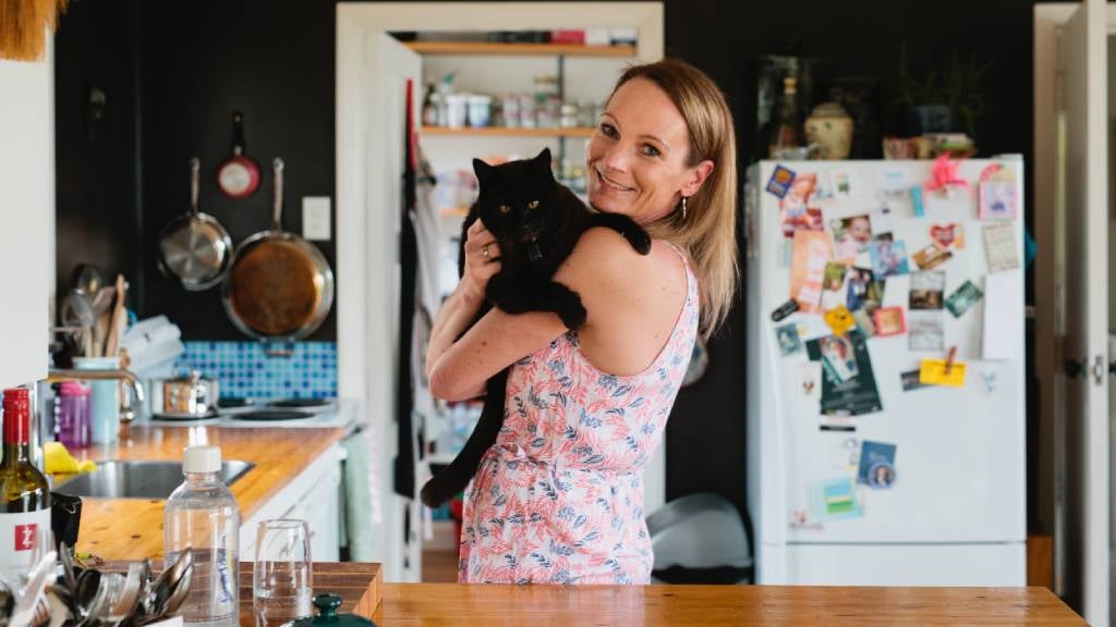 Woman hold cat in kitchen.