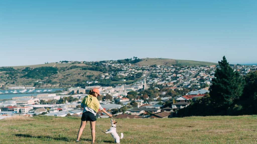 Woman walking with a dog in the park Oamaru, New Zealand