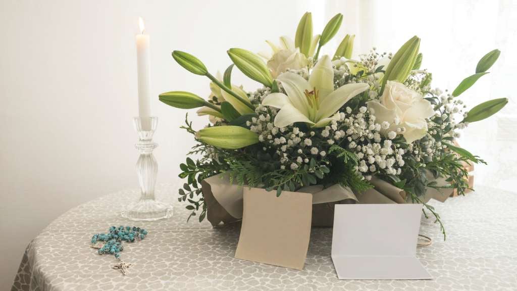 A white bouquet of flowers and candles on a table.
