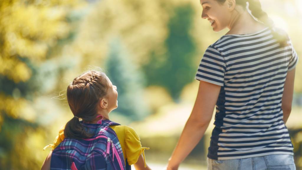 Mother and daughter holding hands walking across the road