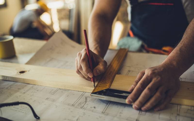 Father plans and uses set square on wooden beam