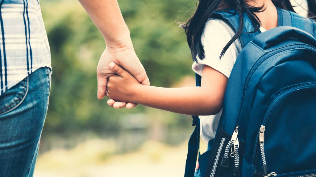 Mother holding daughter's hand as they cross the road