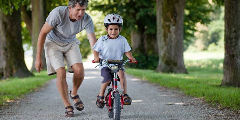 dad pushing child on bike