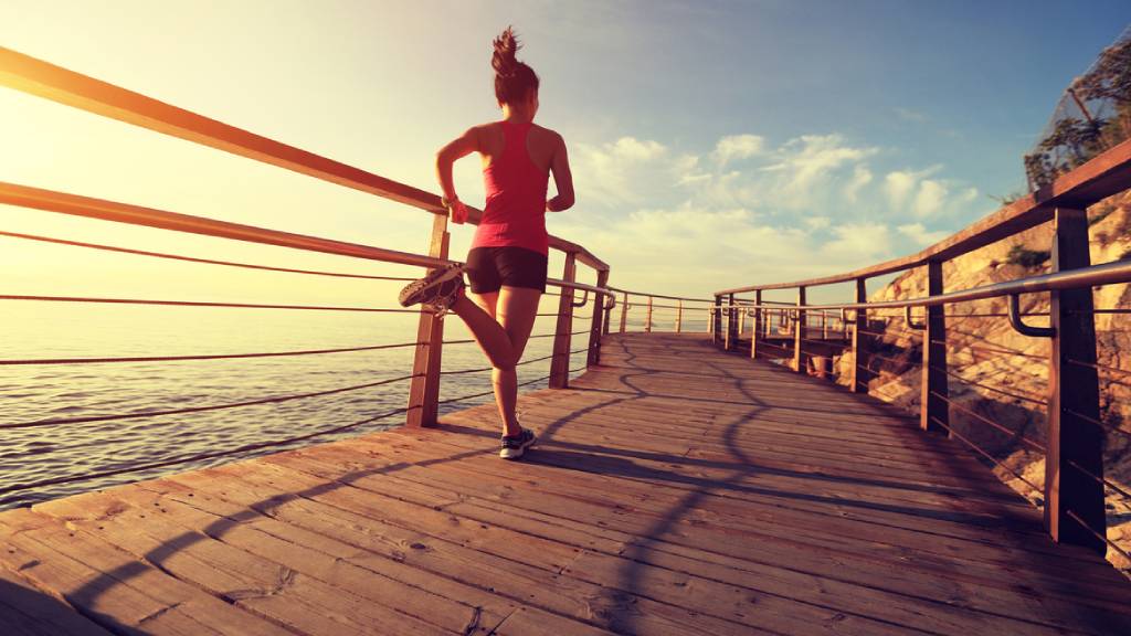 Woman jogging along a beachside boardwalk