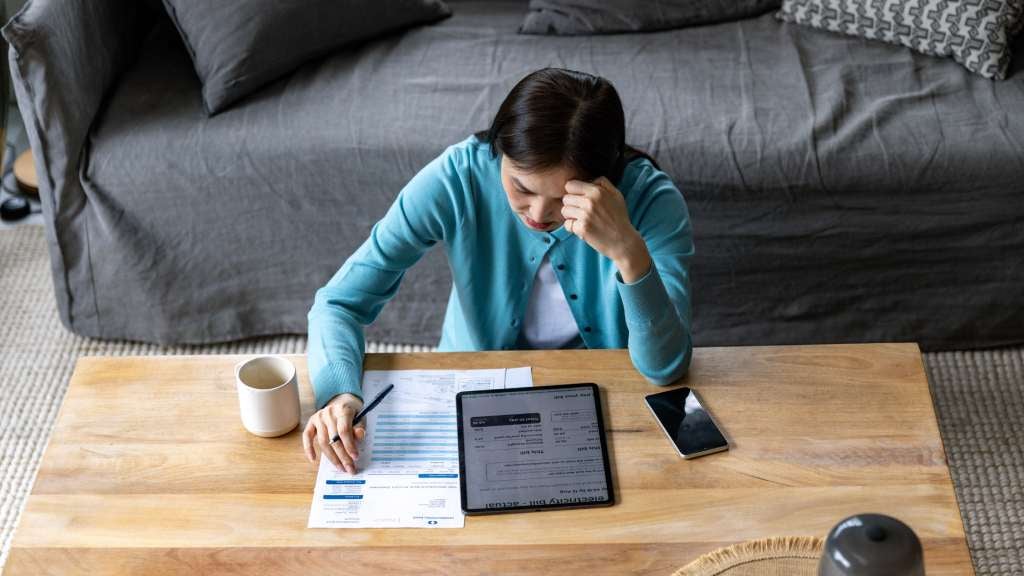Woman sits at her coffee table calculating her household budget