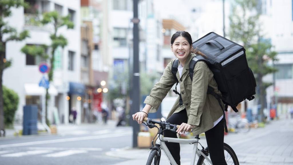 Woman on bike delivers food as delivery rider