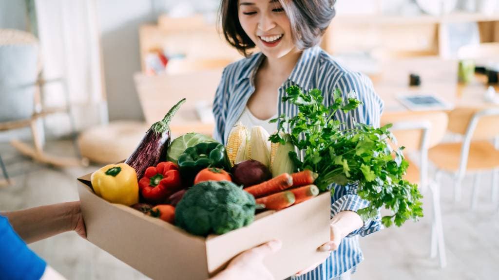 Woman with fresh produce in a cardboard box