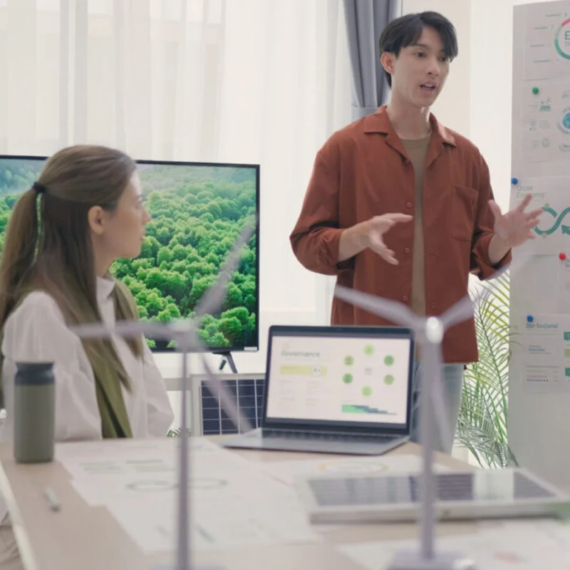 Two people in a meeting room - one person standing and presenting