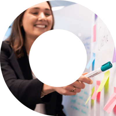 Female actuary writing on post-it-notes and pointing at whiteboard