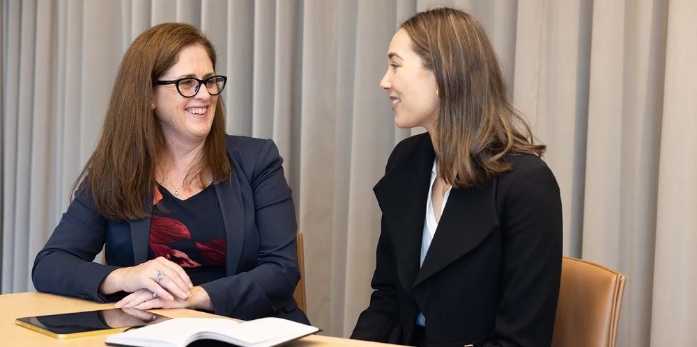 Two actuaries, a mentor and mentee, sitting at a table working