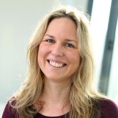 Portrait photo of Sarah Johnson with blonde hair past shoulders, smiling broadly in a burgundy top.