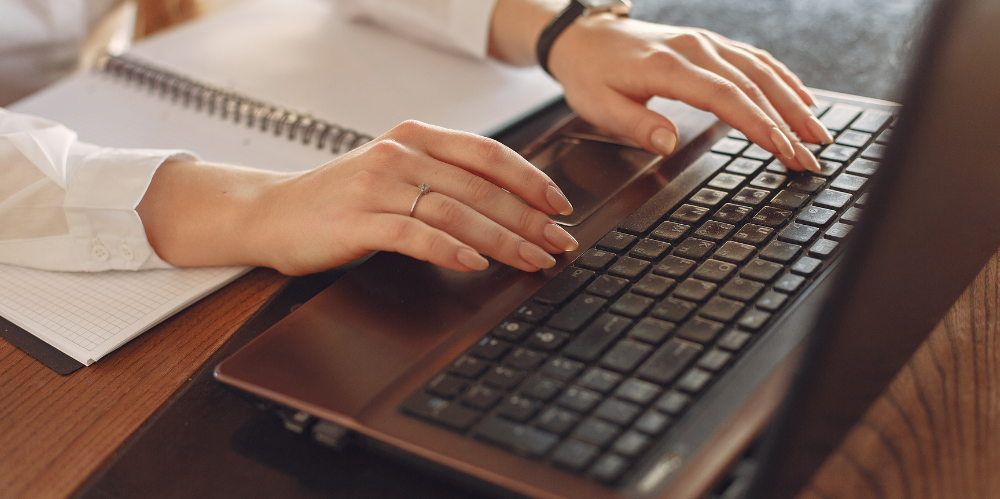 Close up of woman's hands typing on laptop