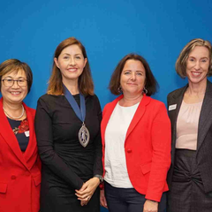 Four professional women stand smiling at the camera.