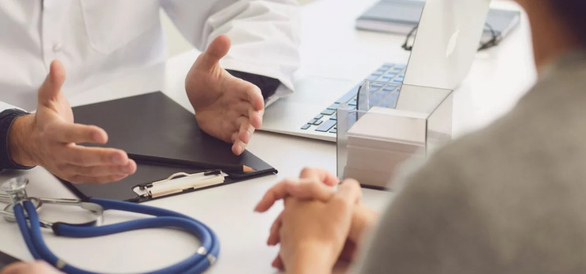 Doctor and patient sitting at a desk - close up of hands