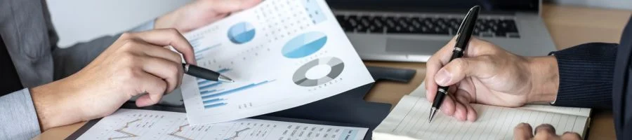 Two hands holding pens looking at graphs close up