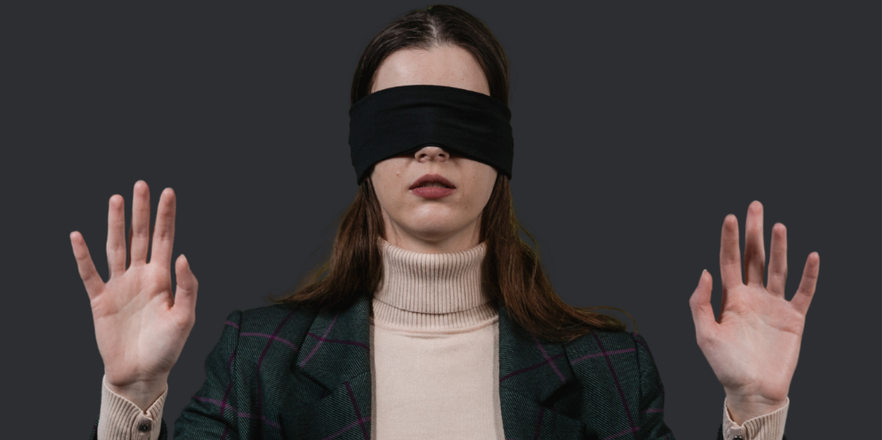 Woman wearing black blindfold with hands raised, palms facing forward