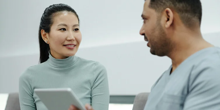 Two people talking looking at an ipad