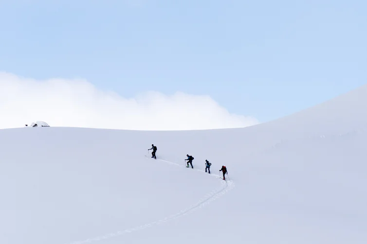 Four people walking to the top of a snow mountain