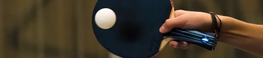 Hand holding ping pong bat hitting ping pong ball