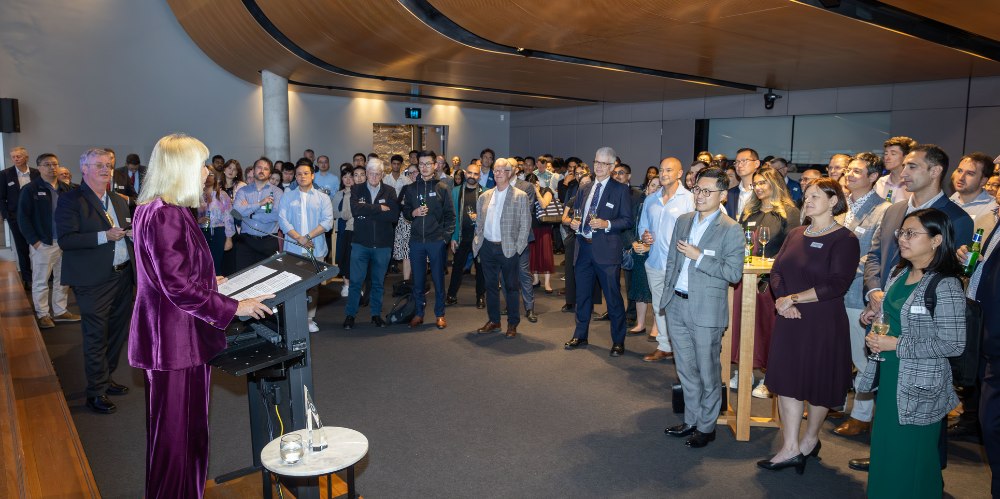 Business event with people standing looking at speaker at the podium in a room with timber ceiling