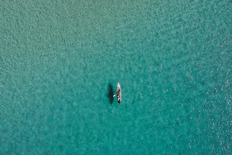 Paddle boarder in middle of beautiful blue ocean