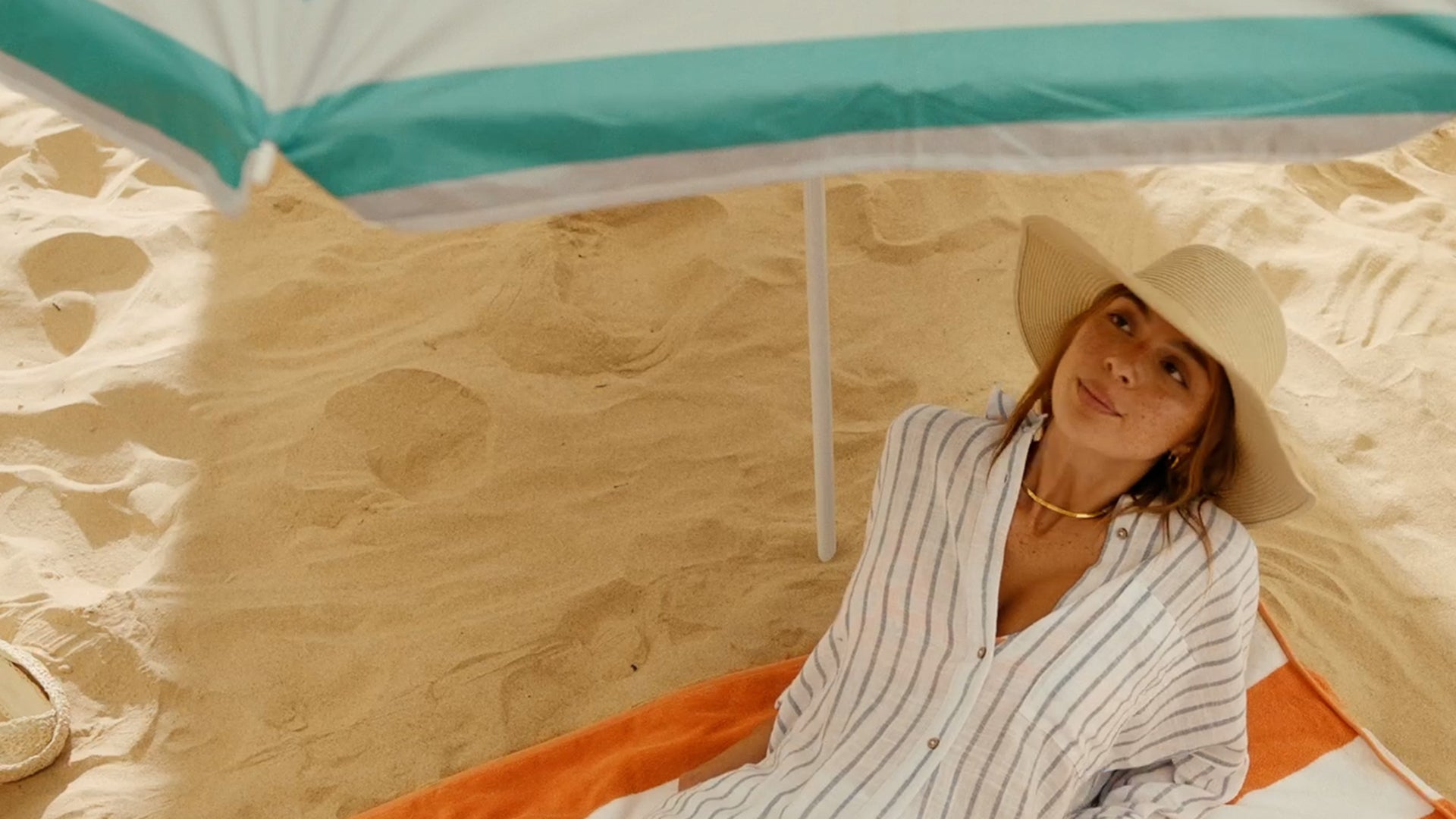 Woman lying under a beach umbrella.