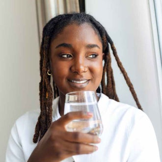 Girl drinking a glass of water. Drinking alcohol increases the risk of cancer.