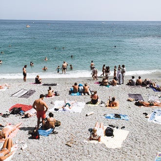 People sitting, standing, lying down and swimming at the beach.
