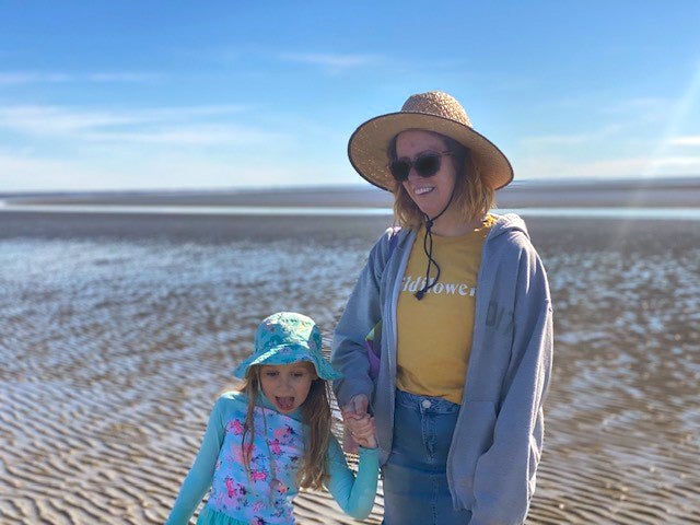 Raelene Buchan on a beach with her daughter. They're both wearing sun-protective clothing.