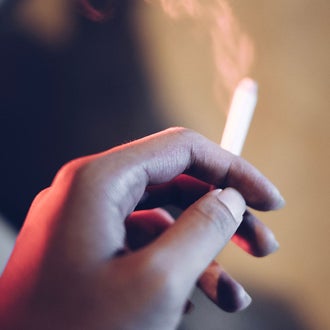 Hand holding a lit cigarette.