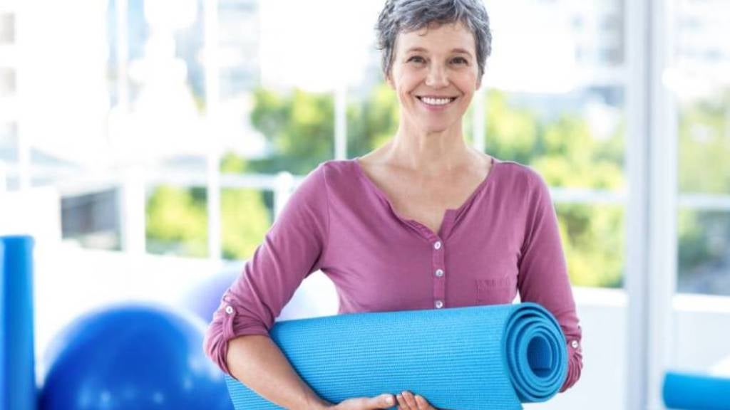 Senior woman holding a yoga mat 