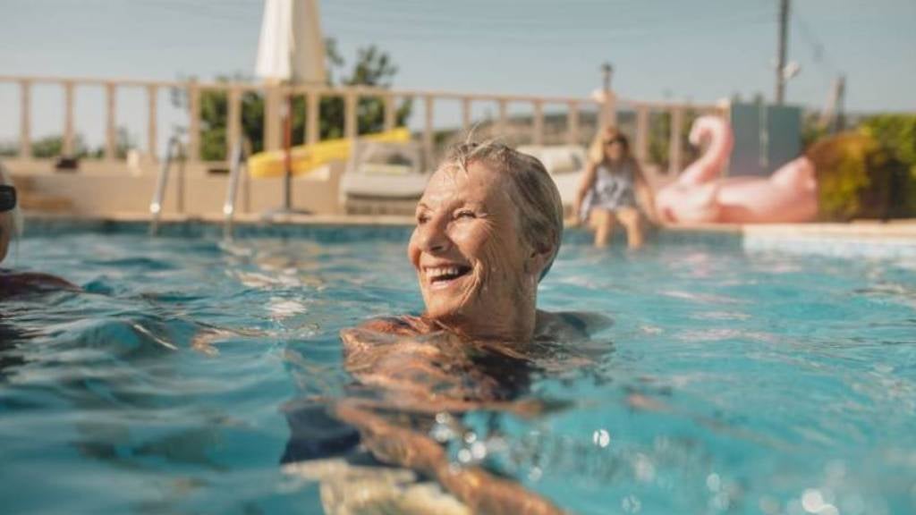 Senior woman in pool swimming.