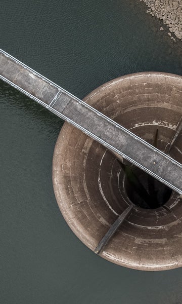 Aerial bird's eye view of low water levels, well below the spillway intake at a reservoir (dam).