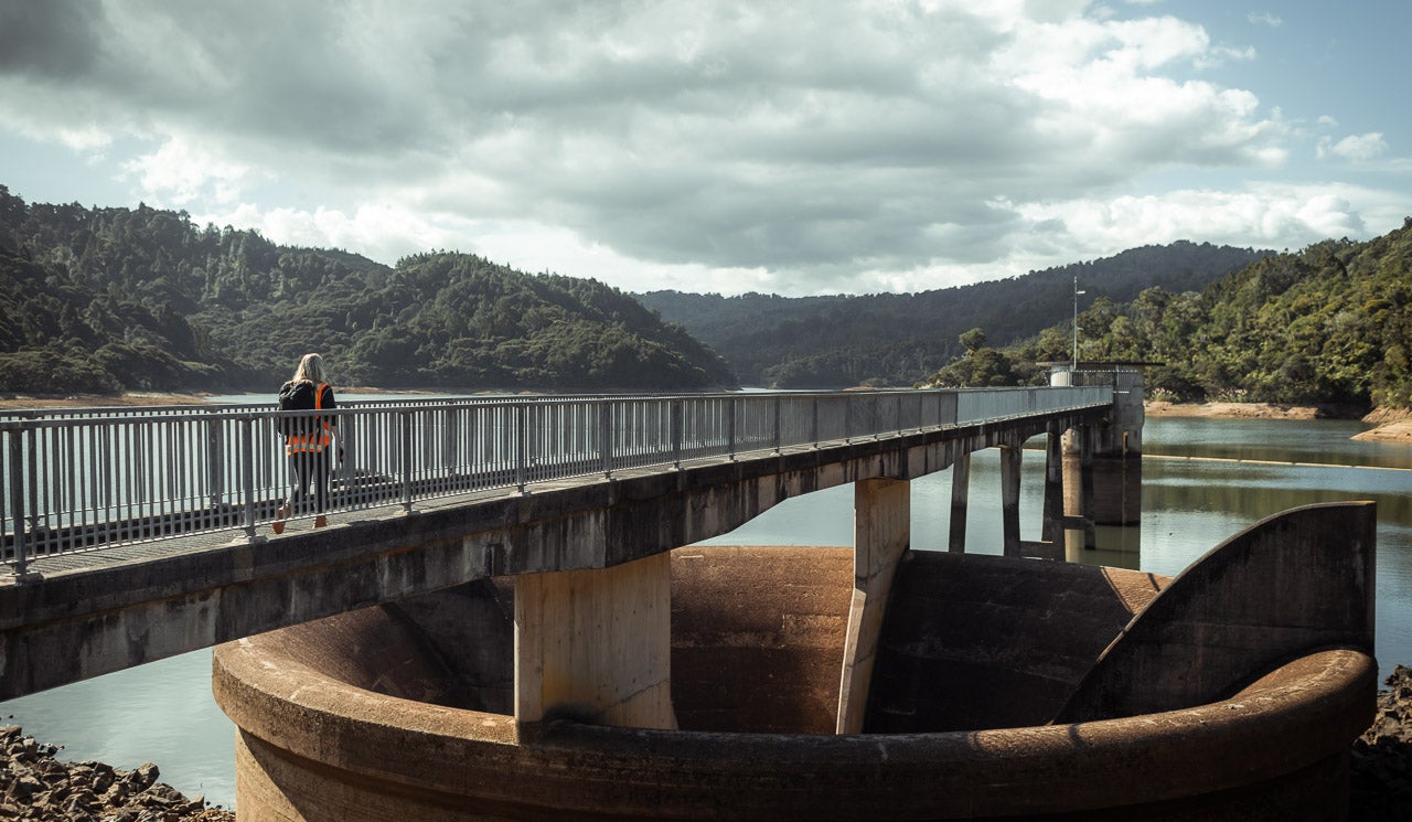 Watercare hydrologist Florence Mills walks along dam towards measurement and gauge positions.